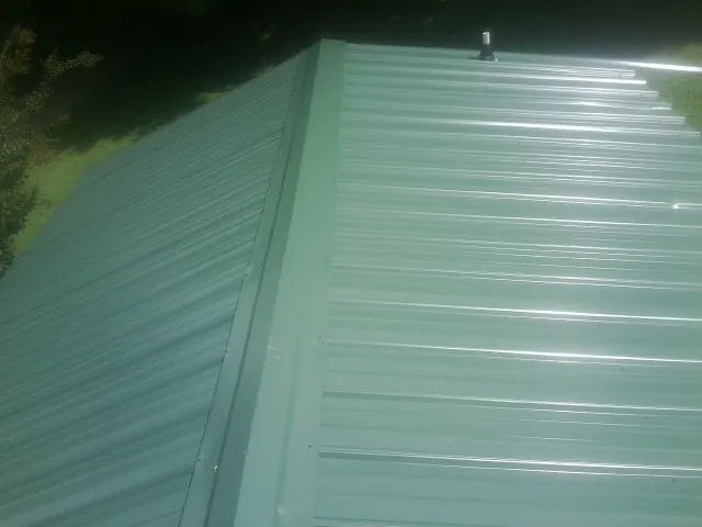 New green metal panels meeting at the ridge of a roof — Flat Roof Repair work by our crew in Cedar Run