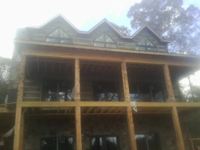 Dormers and porch framing on a large log home under construction — Roof Coating work by our crew in Cedar Run