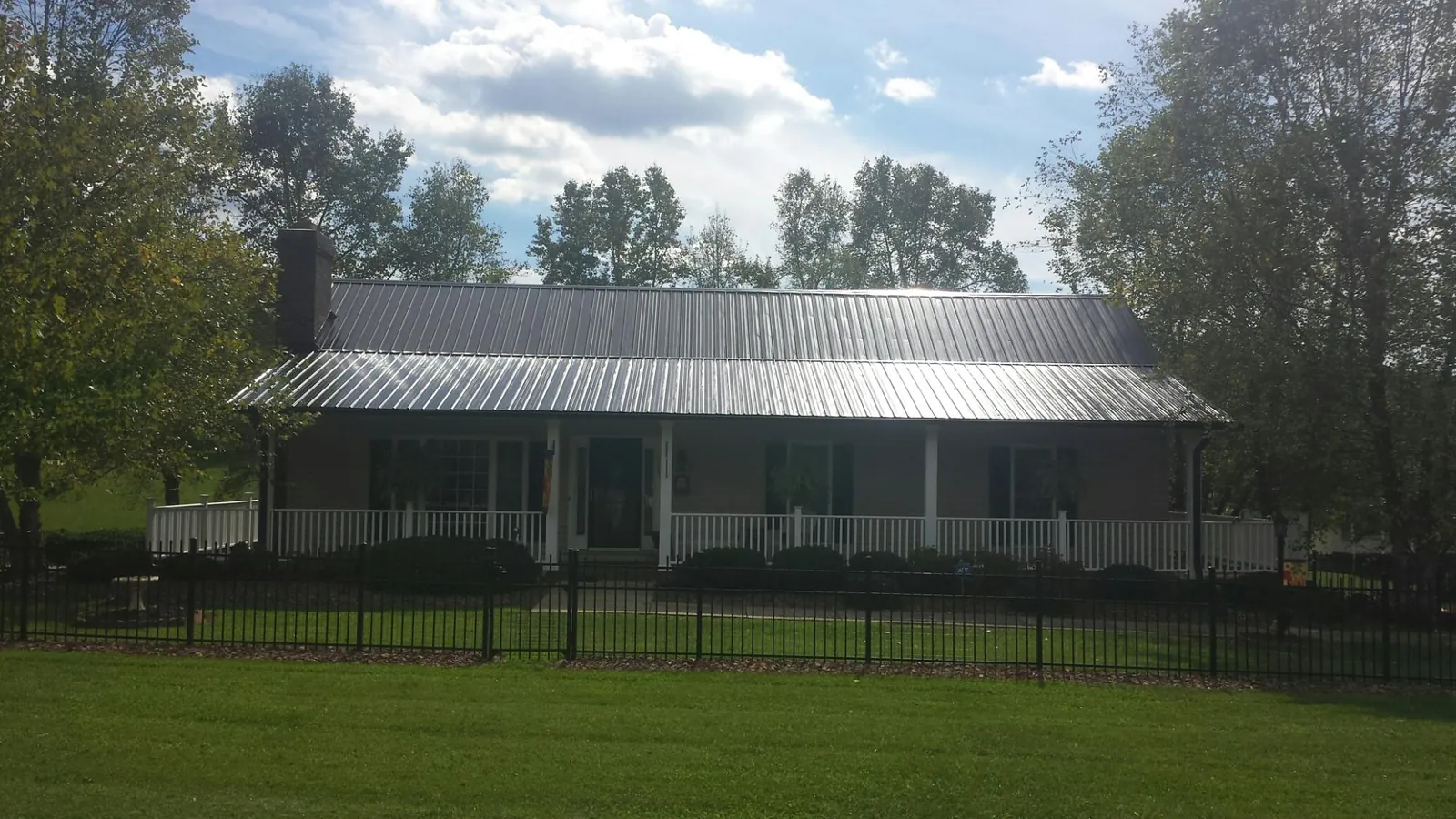 Gray metal roof on a brick ranch with a full width front porch — Gutter Guard Installation work by our crew in Cedar Run