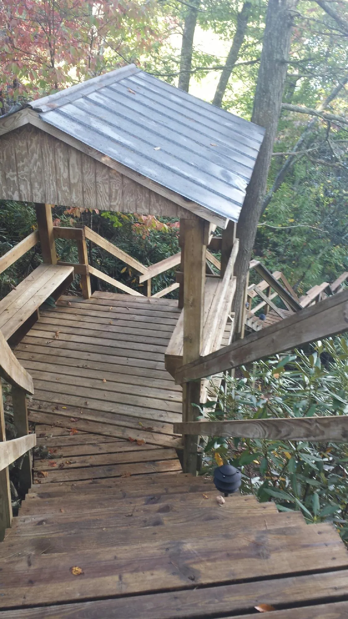 Metal roofed shelter over wooden steps on a wooded walkway — Skylight Repair & Installation work by our crew in Cedar Run