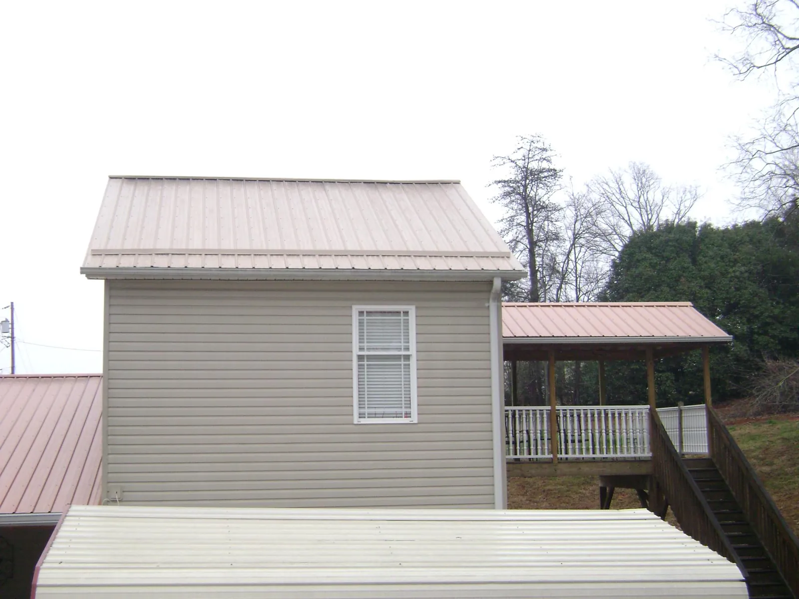 Tan metal roofs on a two story addition and attached porch, from a Roof Replacement job in Cedar Run