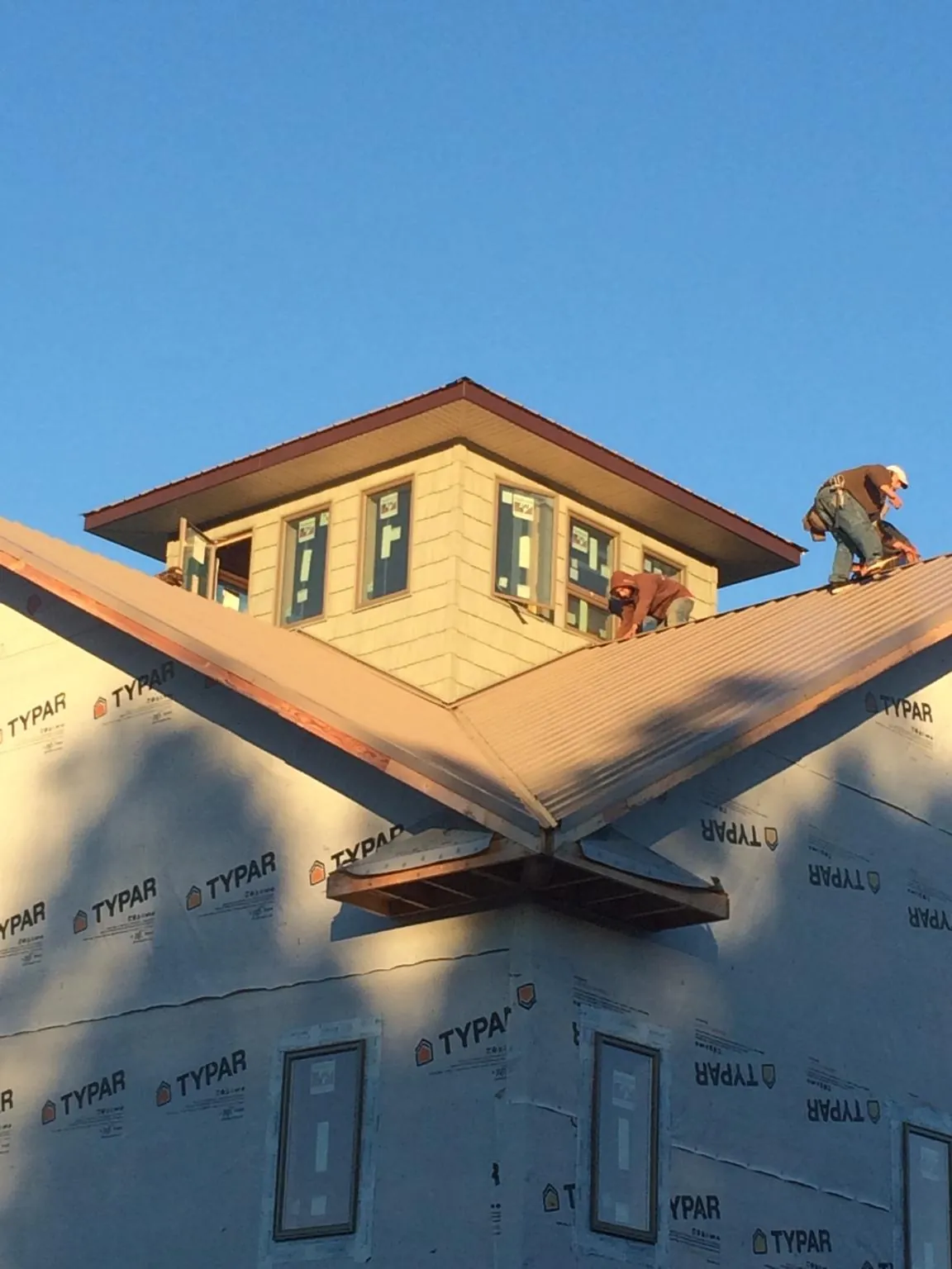 Roofers working around a rooftop cupola on a new metal roof at sunset — Roof Waterproofing in Cedar Run by Roofing Brothers